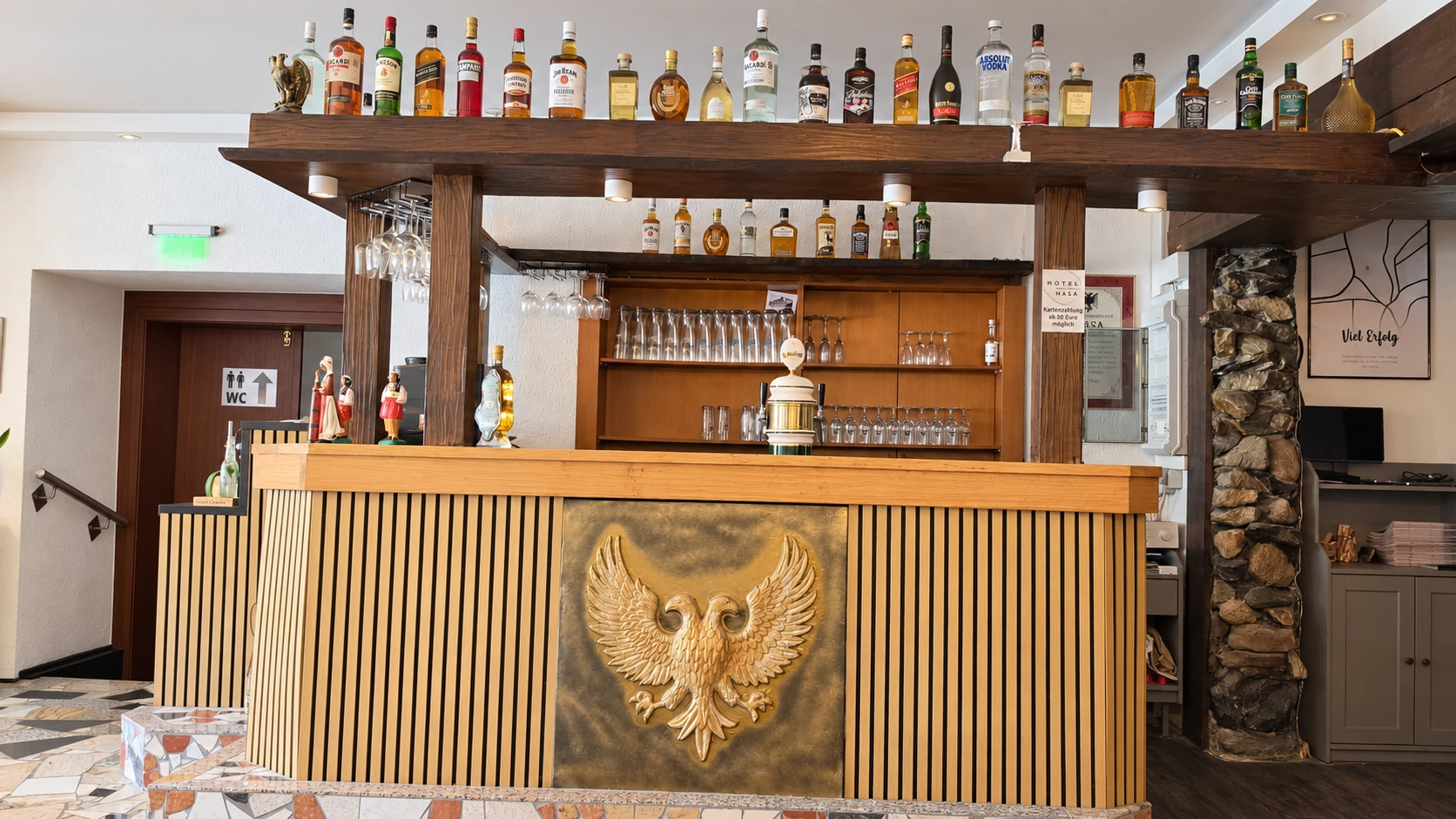 Bartheke im Hotel Hasa mit vollem Spirituosenregal und goldenem albanischen Doppeladler-Relief.