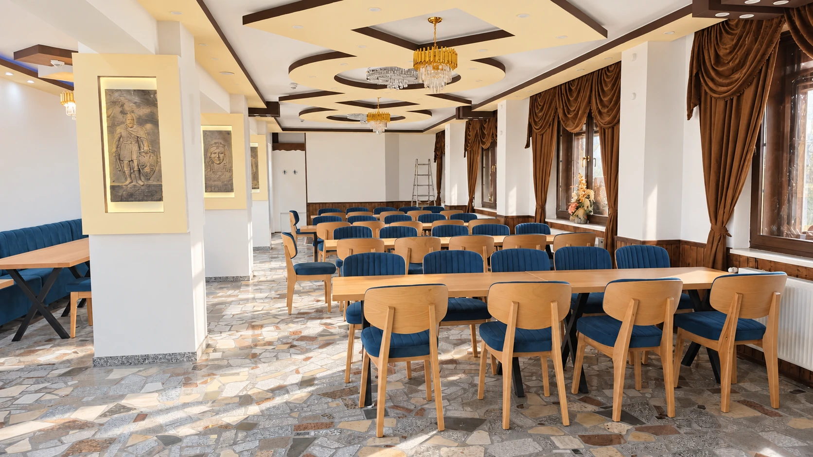 Speisesaal im Hotel Hasa mit bronzenen albanischen Wandreliefs und blauen Polsterstühlen.